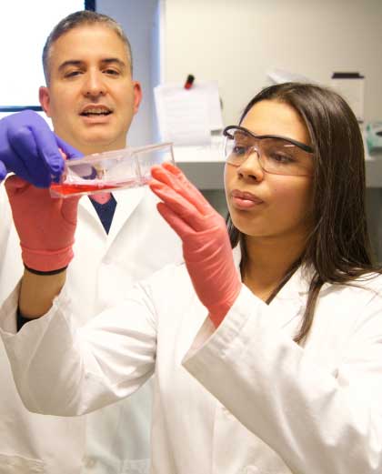 professor assists student in a lab